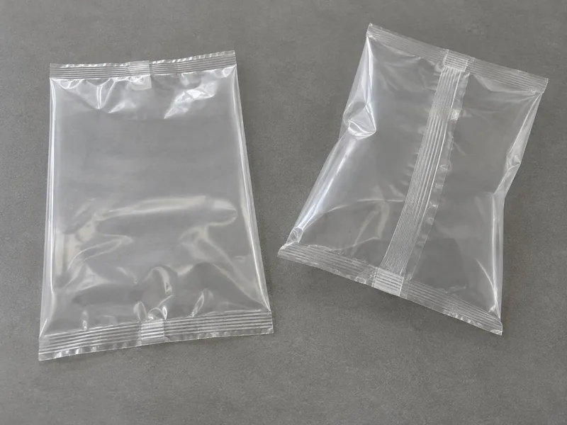 Two empty unprinted clear pillow bags, showing end seals and a longitudinal fin seam.